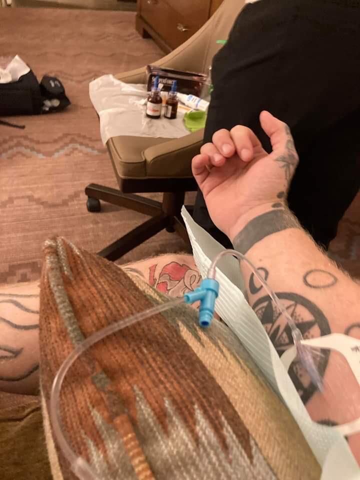 A person with a tattoo on their arm has an iv in their arm