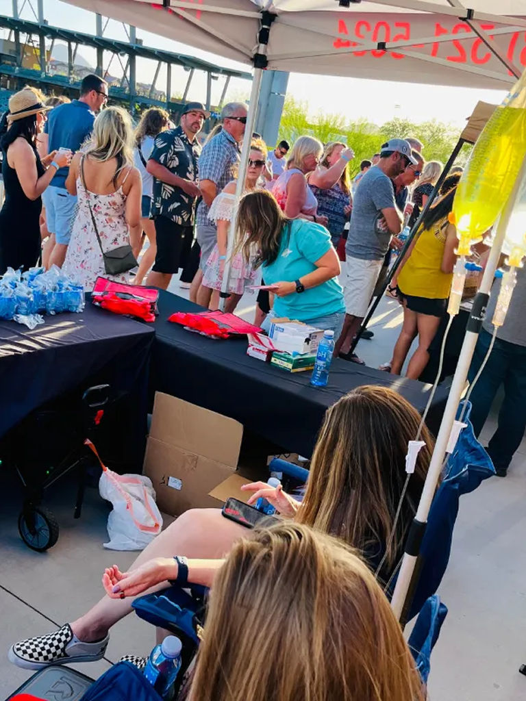 Two men are sitting on a bench with iv bags in their legs.