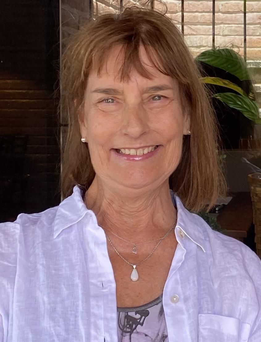 A woman in a white shirt is smiling for the camera.