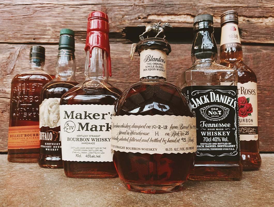 A group of bottles of whiskey are sitting on a wooden table.