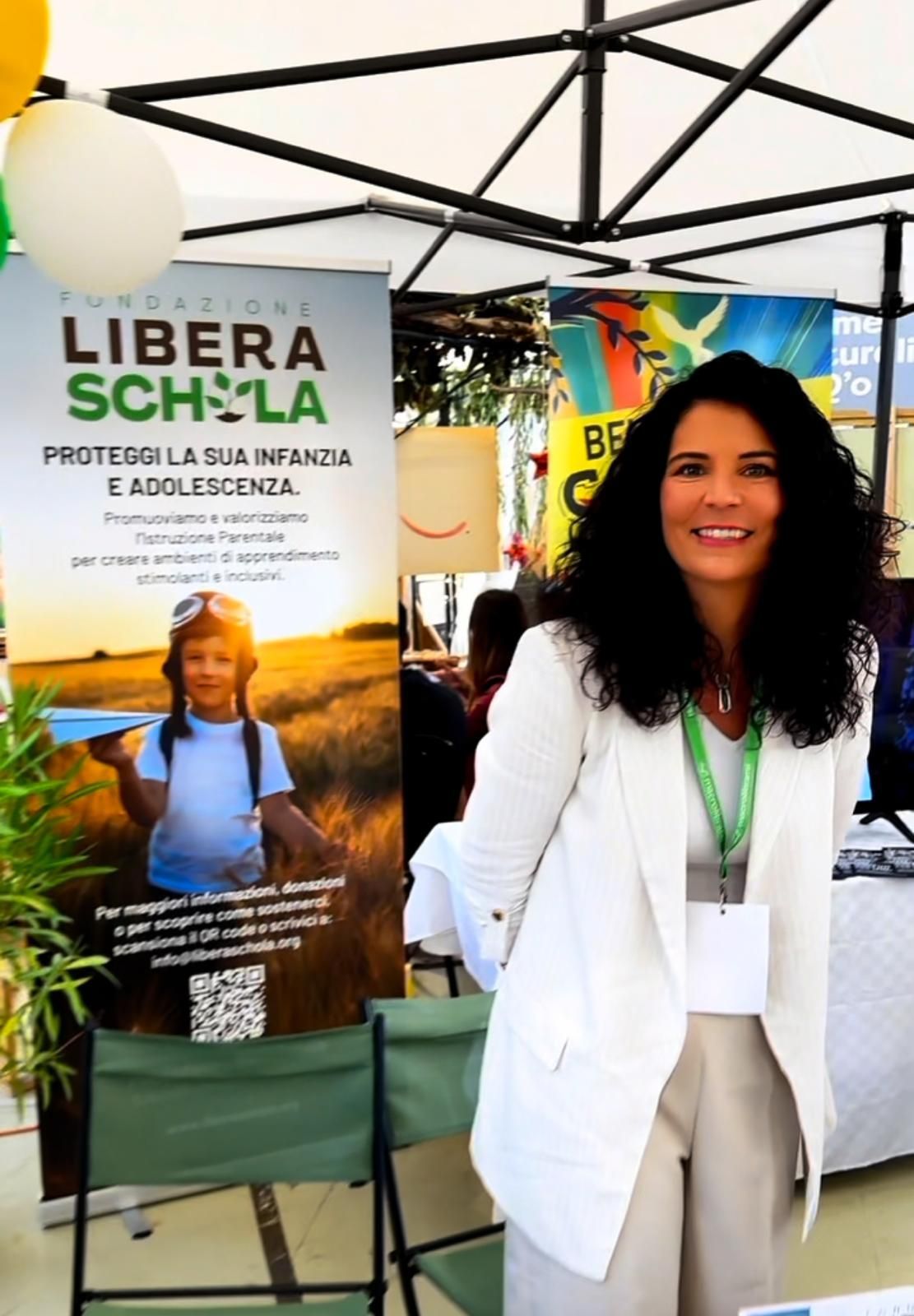 Camera luminosa con zona salotto vicino alle finestre, due poltrone, tappeto, tavolini laterali e piante.