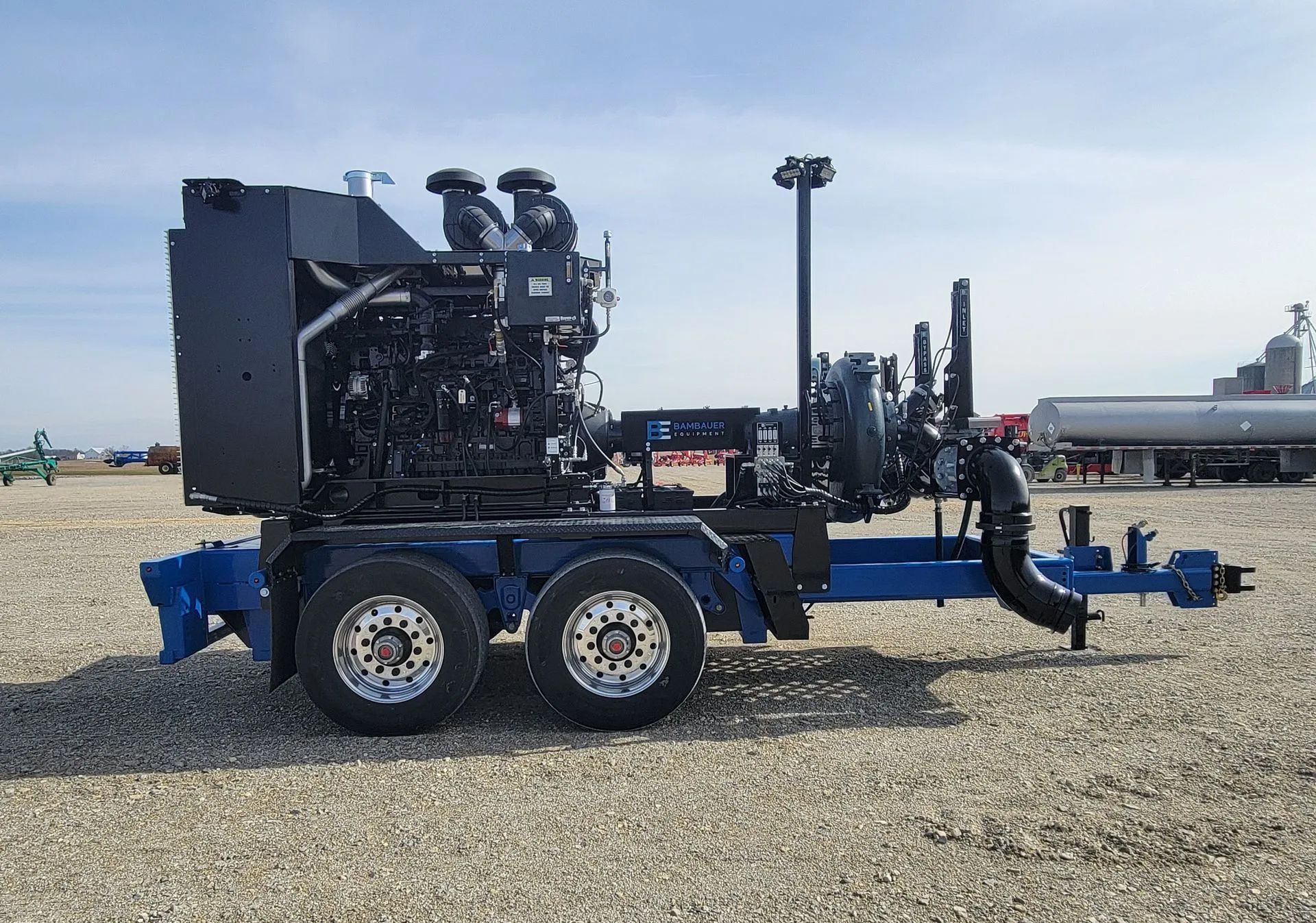 Blue industrial trailer-mounted machine parked on gravel under a clear sky