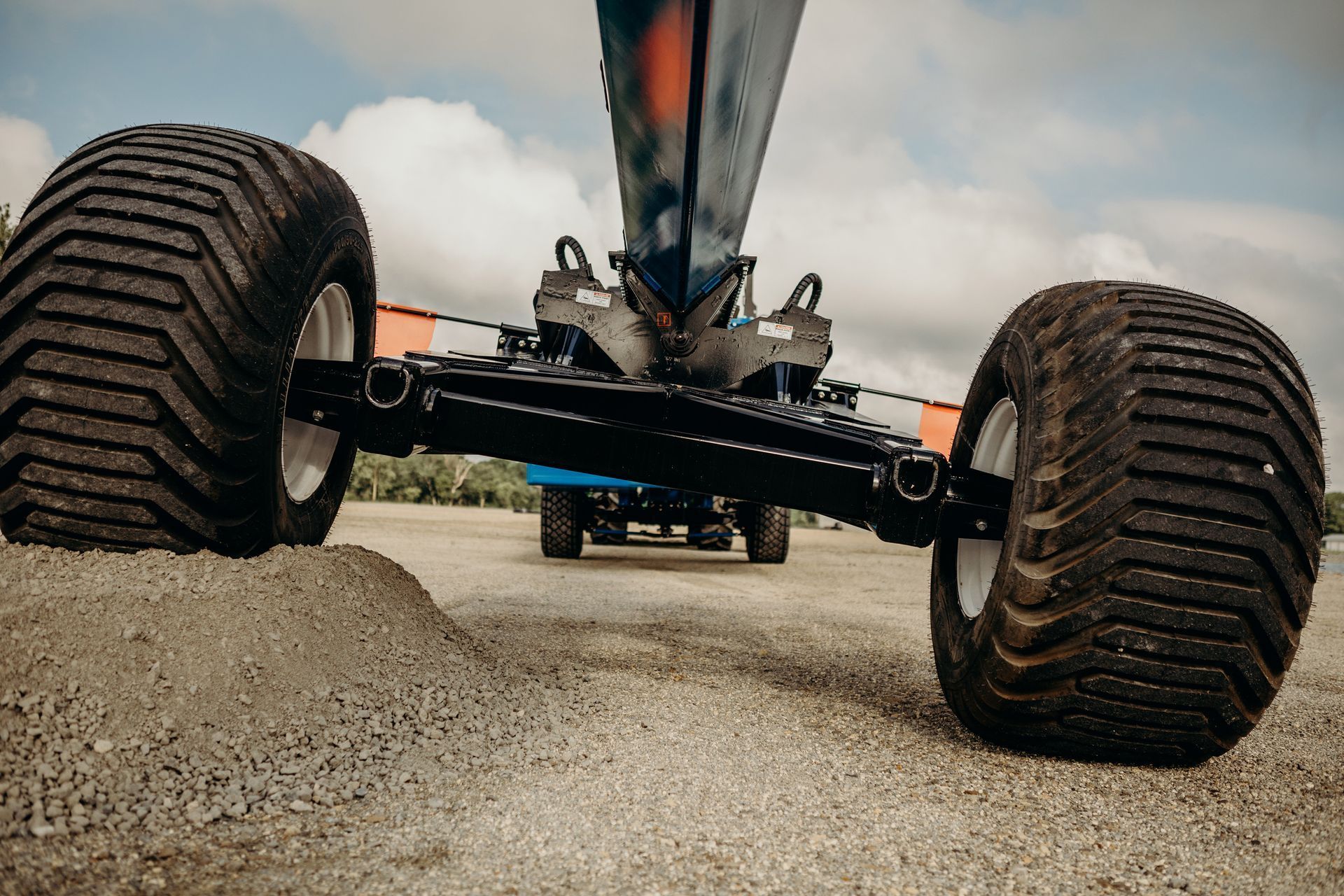 Low-angle view of an off-road vehicle’s large tires kicking up dirt on a gravel road
