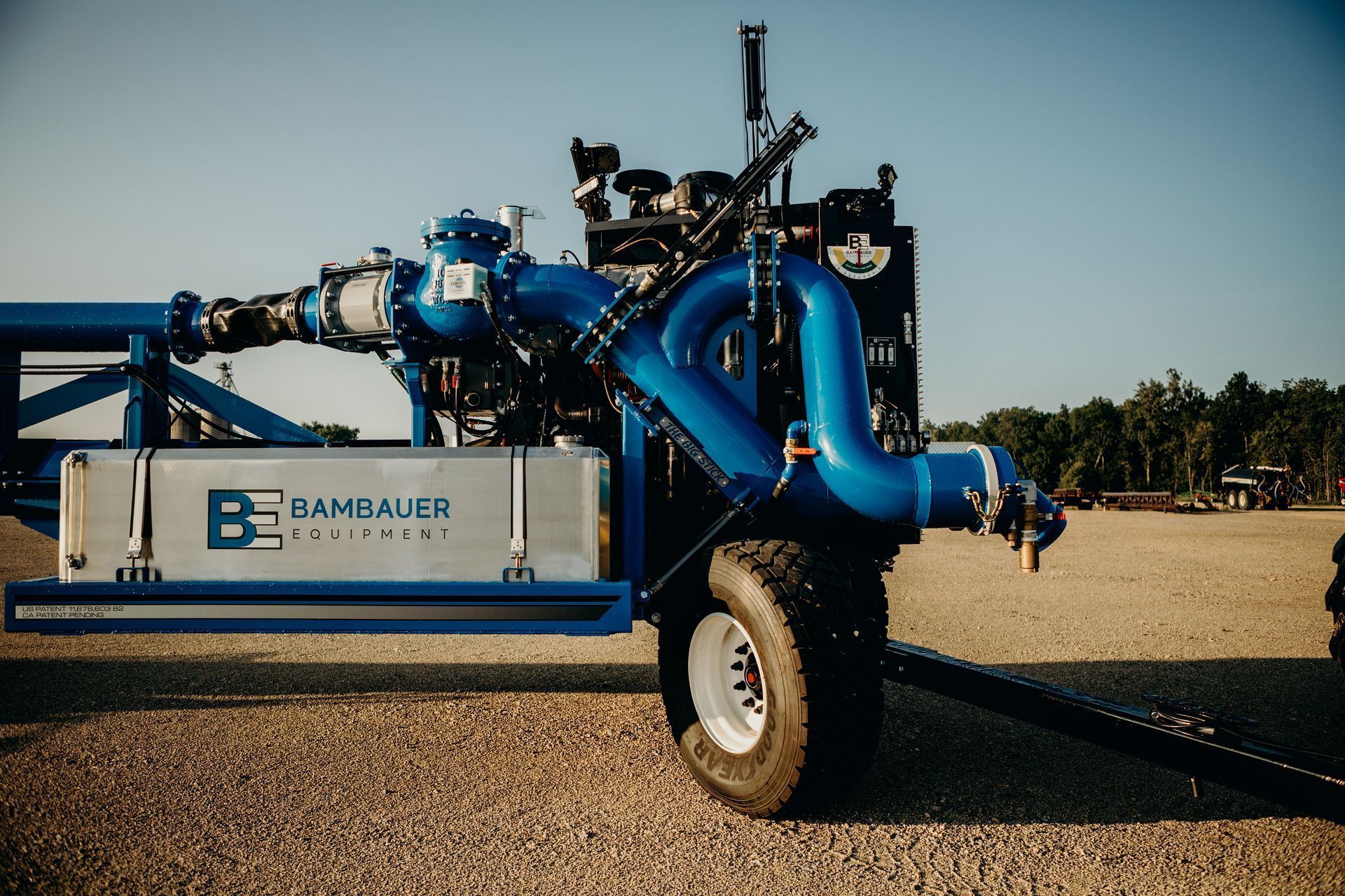 Blue industrial pump mounted on a trailer in a gravel lot, with tanks and hoses attached