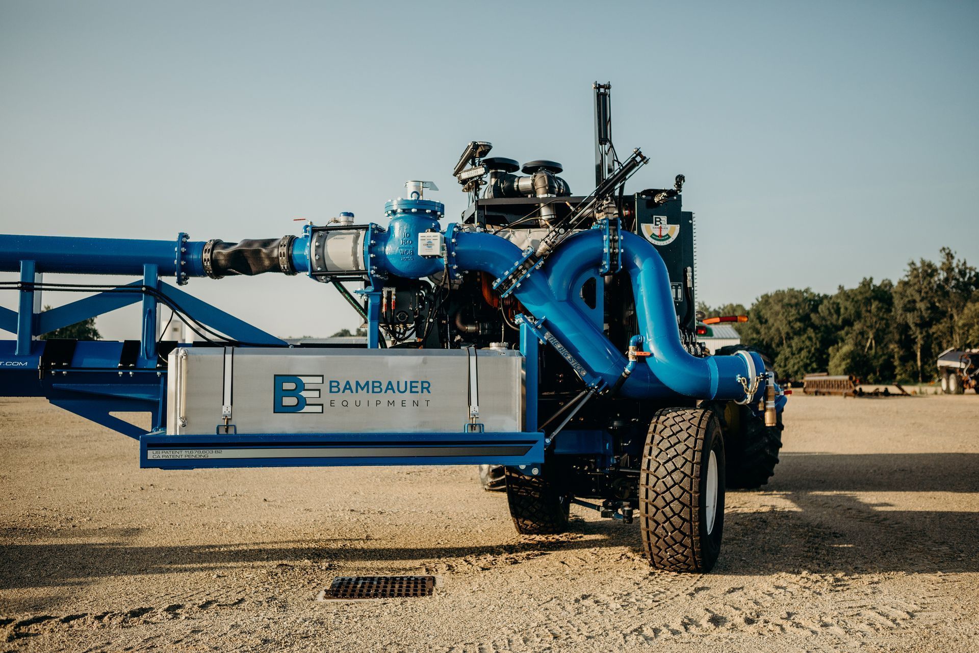 Blue agricultural irrigation machine with large pipes and wheels on a gravel field