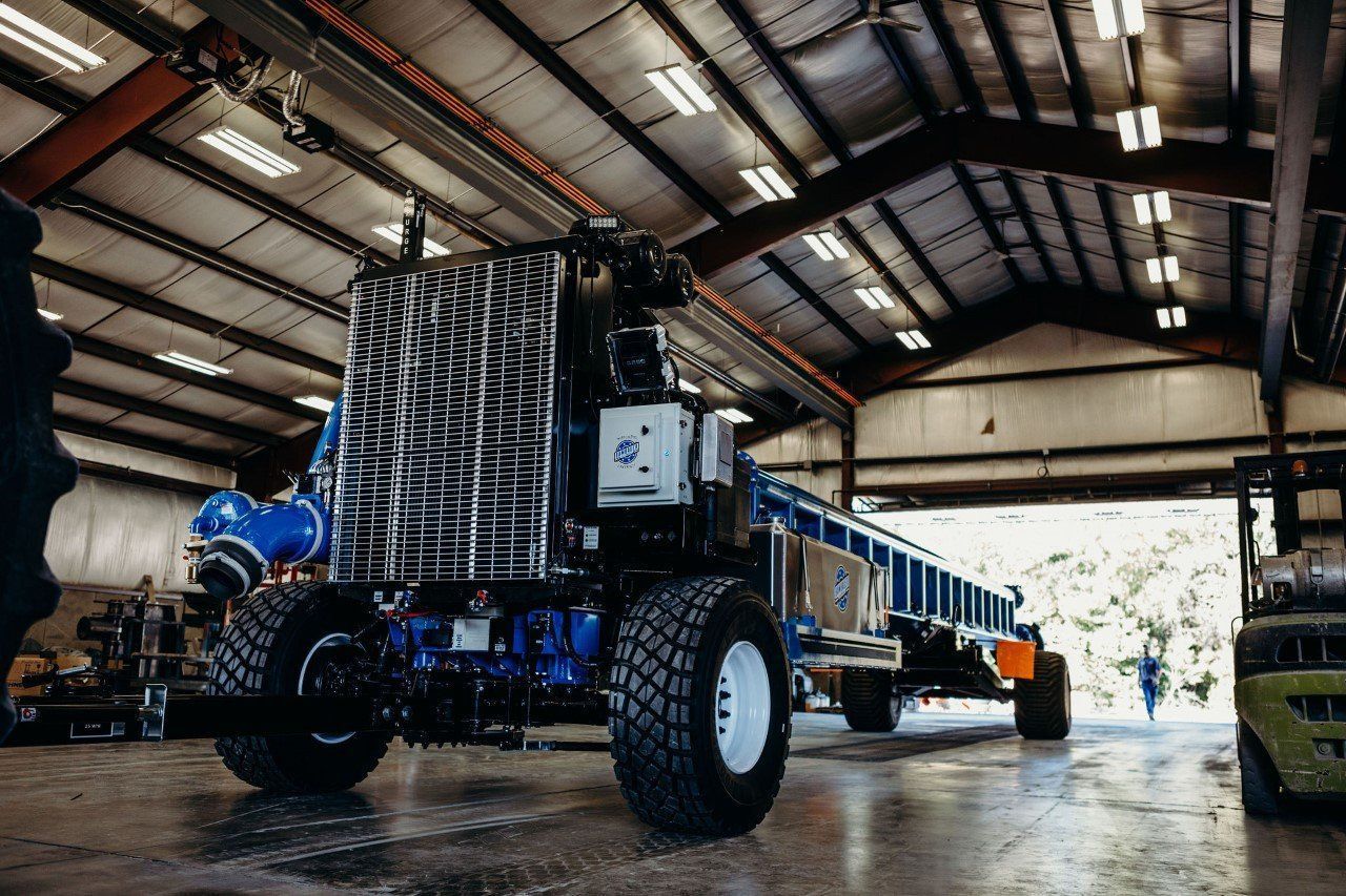 Large off-road vehicle with oversized tires inside a warehouse, seen from a low angle.