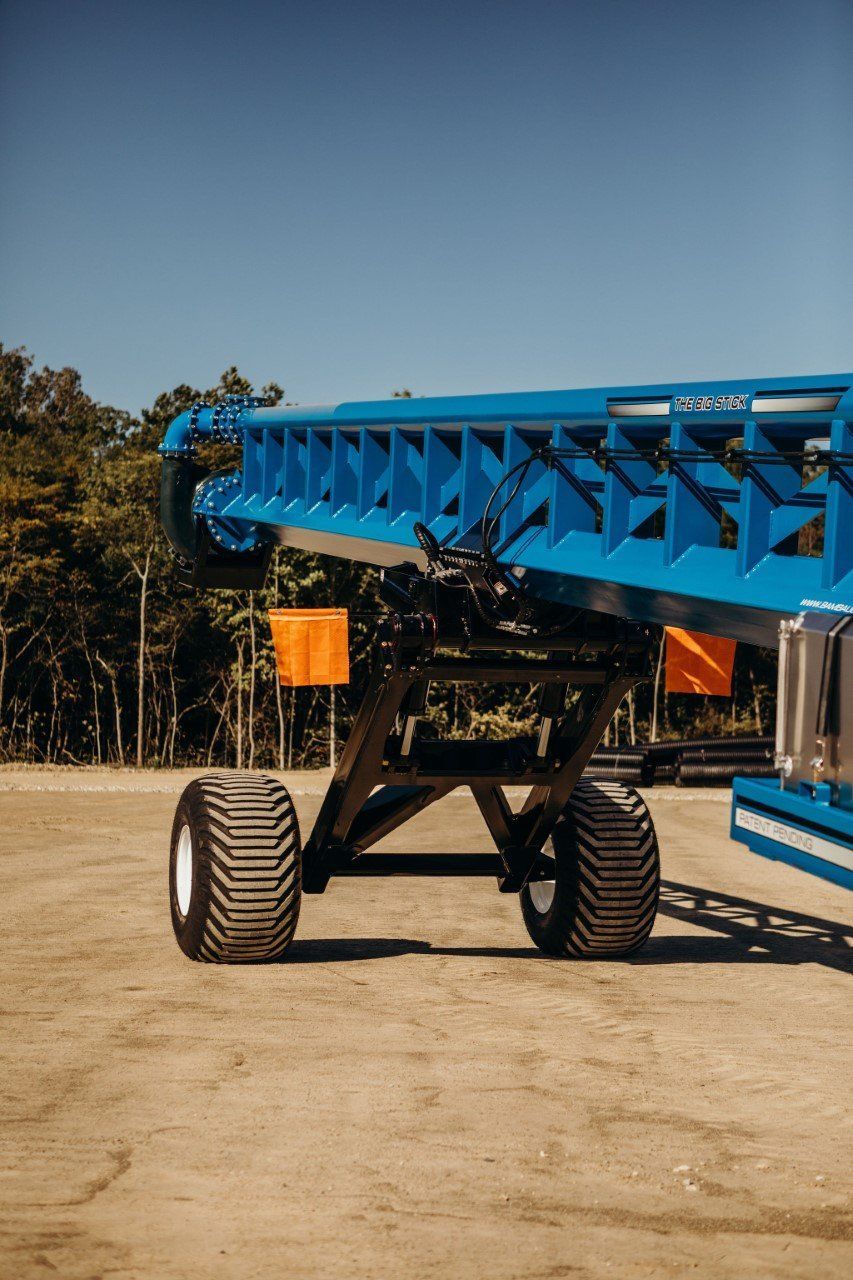 Blue agricultural machine with large tires parked on a dirt lot outdoors