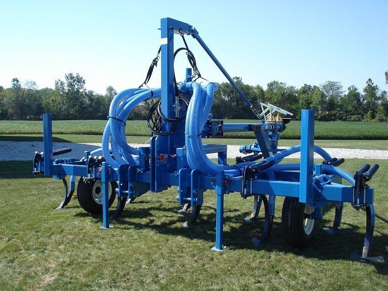 Blue farm machine on grass field under clear sky