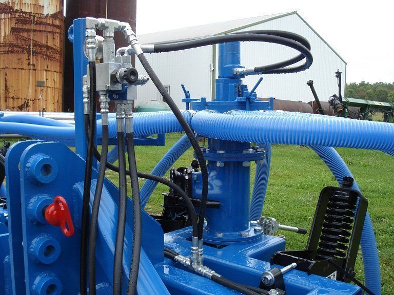 Blue industrial pump and hoses mounted outdoors on a grassy site.