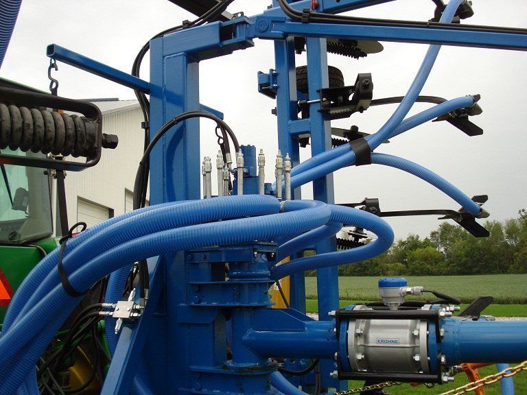 Blue agricultural machine with hoses and metal parts in a field
