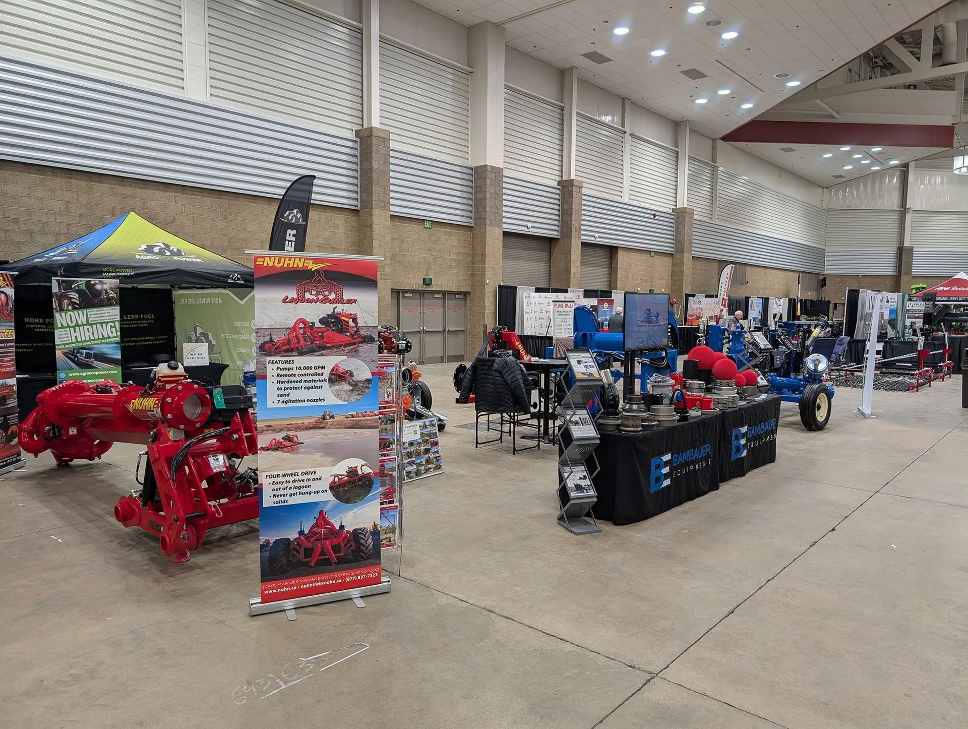 Indoor expo hall with red and blue off-road vehicles, vendor booths, and promotional banners