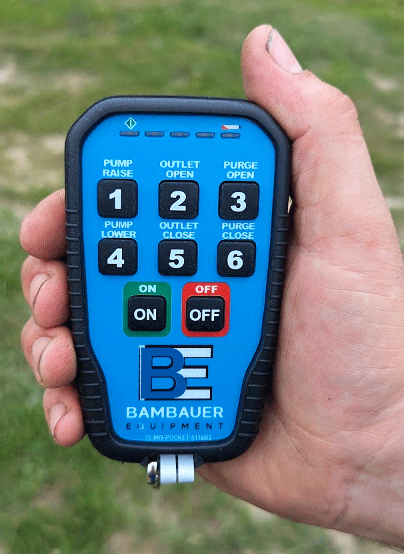 Hand holding a blue-and-black pump control remote with numbered buttons and red on/off switches.