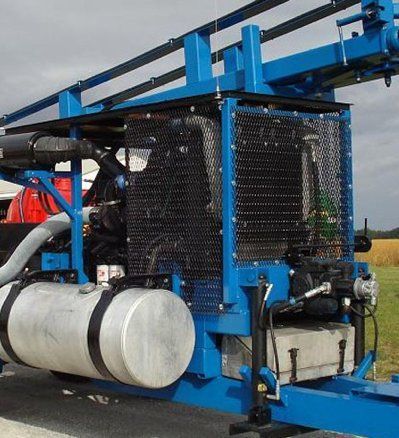Blue agricultural machinery with a metal cage and tanks in a field