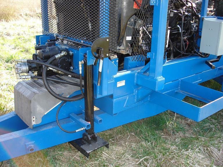 Blue hydraulic machine base with hoses and metal frame on grass outdoors
