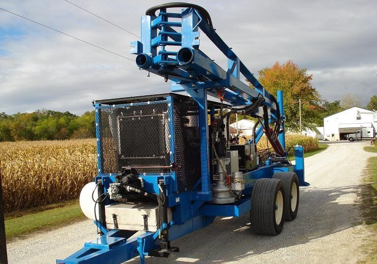Blue agricultural machine parked beside a cornfield on a rural road