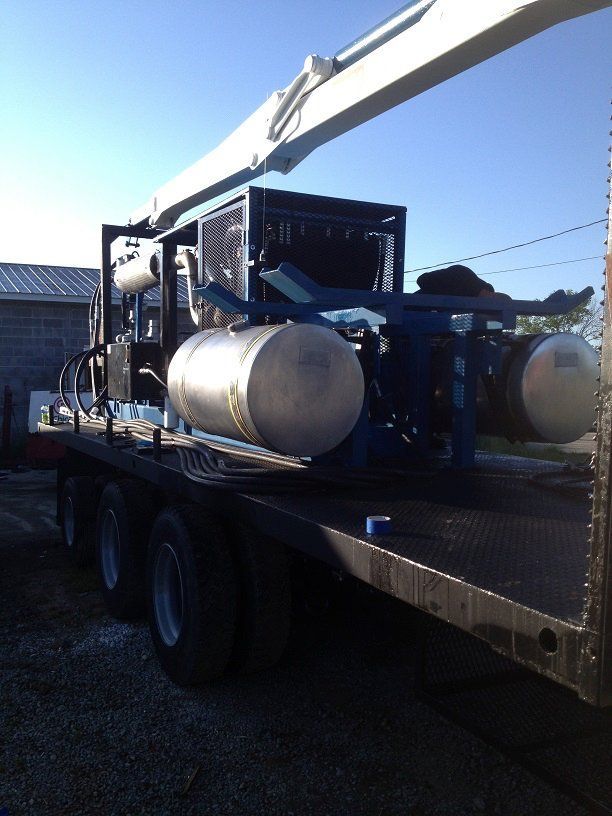 Truck carrying large metal tanks on a flatbed trailer in bright sunlight