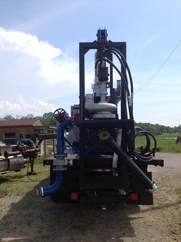 Large blue industrial drilling rig on a truck, parked outdoors under a bright sky.