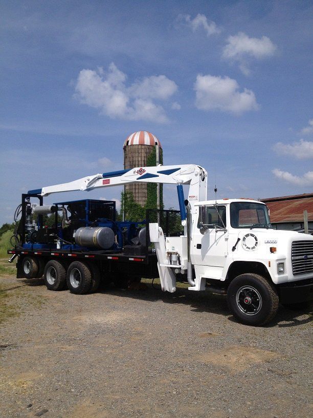 White cement mixer truck on a gravel lot under a blue sky