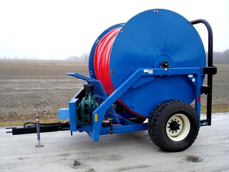 Blue hose reel trailer on a concrete surface, with a red hose and large wheels.