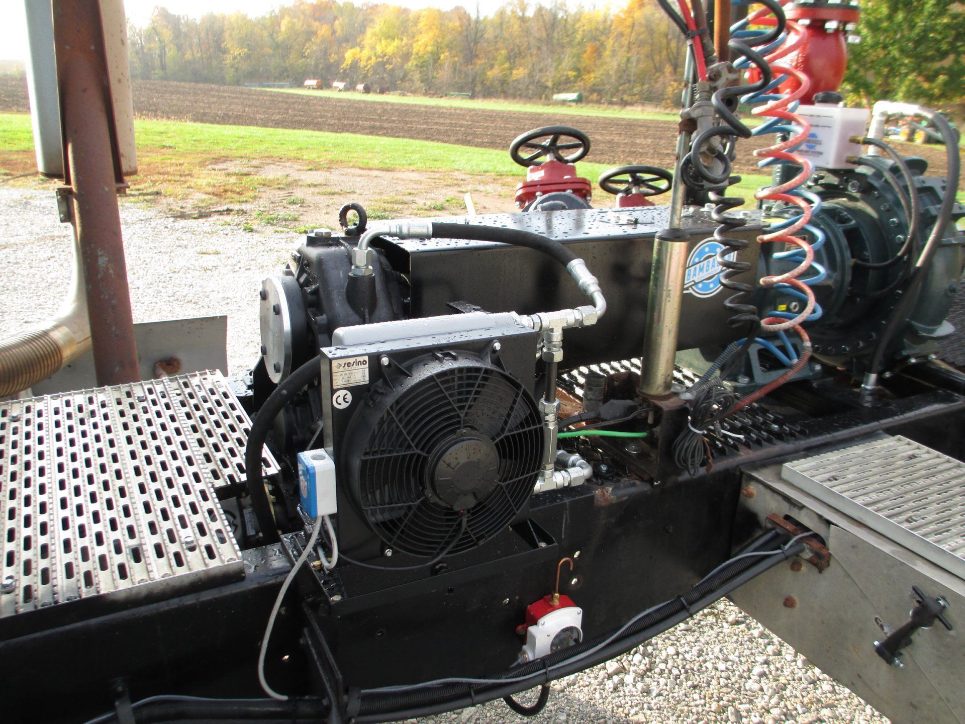 Industrial machinery with a black fan and coiled hoses mounted on a metal platform outdoors