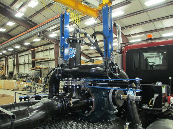 Large industrial machine with blue frame and black piping inside a factory workshop