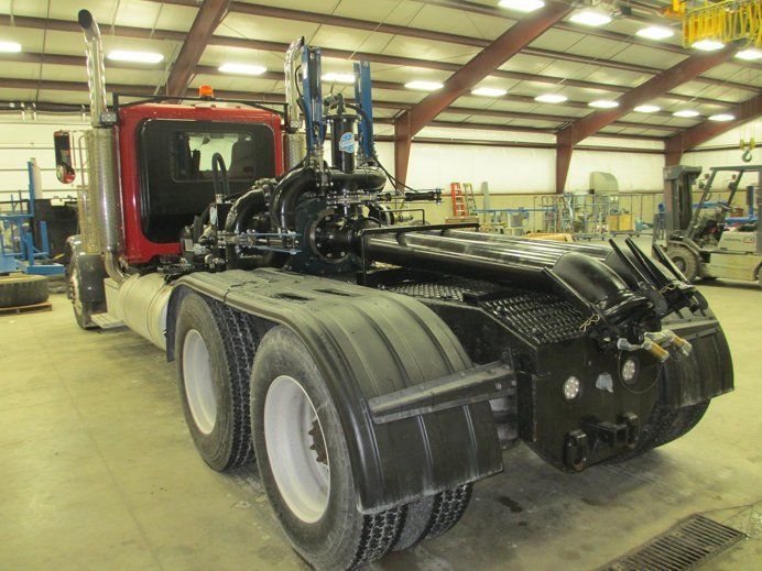 Red truck cab chassis in a warehouse with exposed engine and rear wheels removed