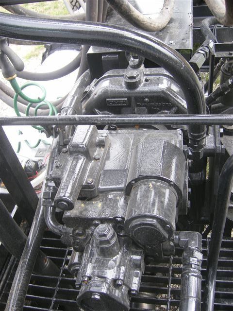 Close-up of a metal engine or machinery with hoses and pipes in a workshop setting