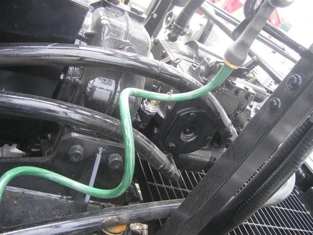 Close-up of a car engine bay with black components and a green hose attached.