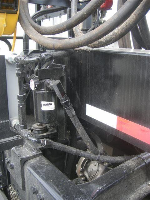 Close-up of black industrial machinery with hoses and metal fittings on a vehicle.
