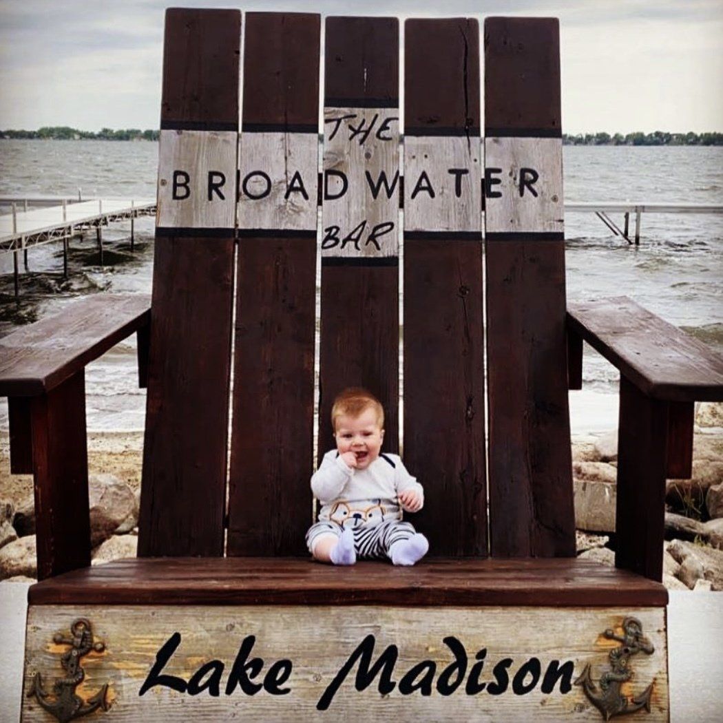 A baby is sitting in a wooden chair that says lake madison