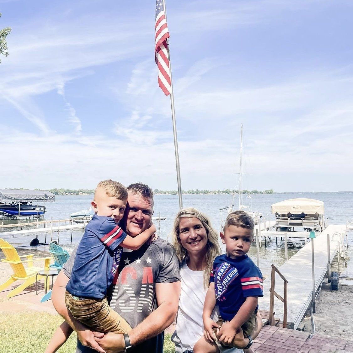A family is posing for a picture in front of a lake.