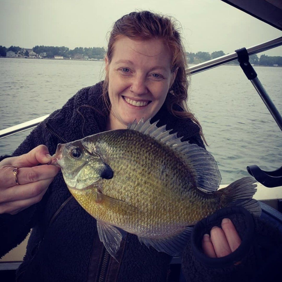 A woman is holding a fish in her hands and smiling