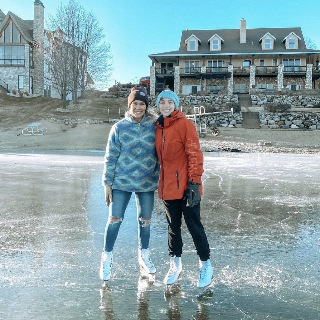 Two women are standing next to each other on a frozen lake.