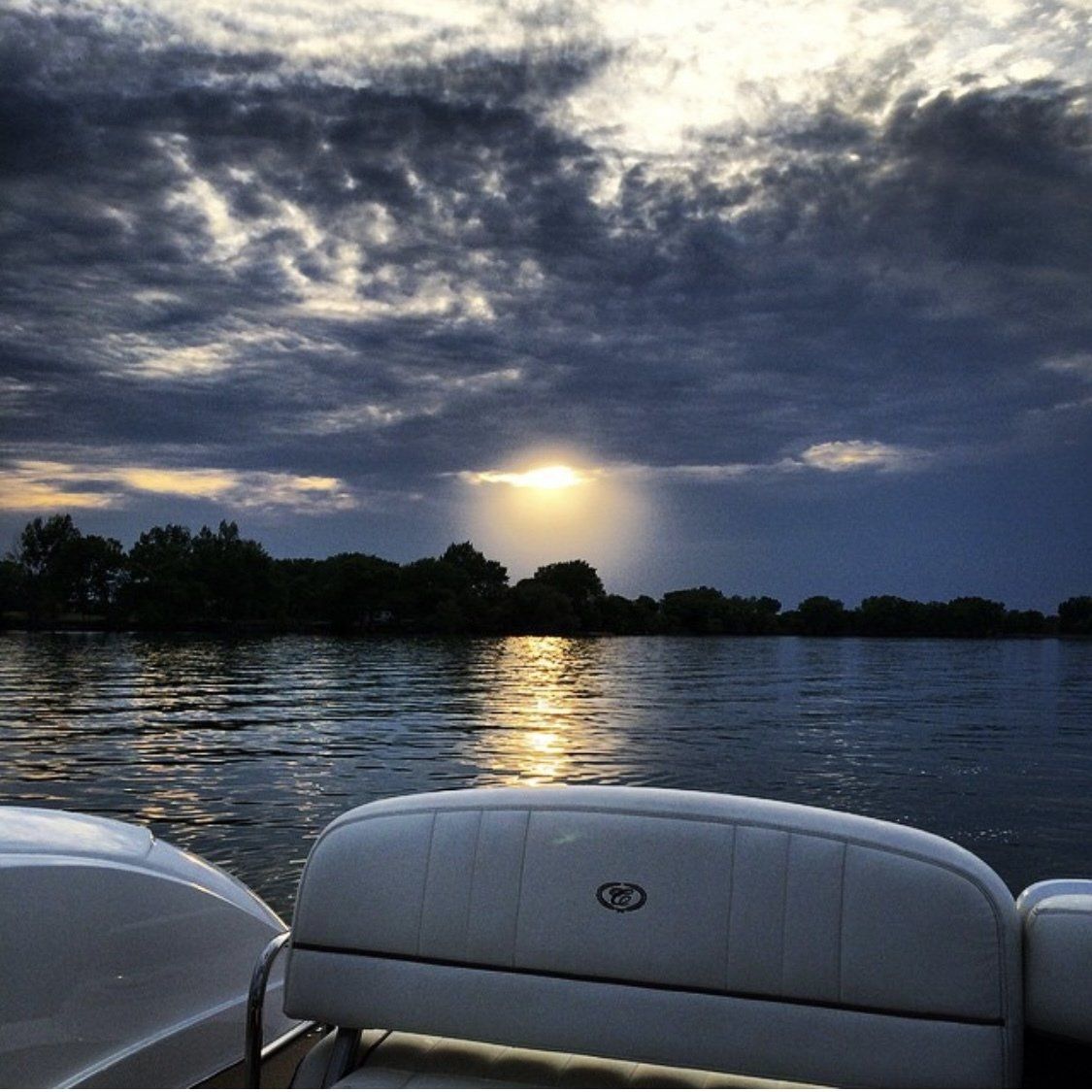 The sun is shining through the clouds over a body of water
