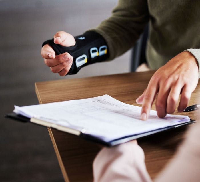 A man wearing a wrist brace is signing a document A man wearing a wrist brace is signing a document