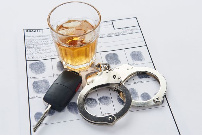 A man is holding a bottle of beer while driving a car. A man is holding a bottle of beer while driving a car.