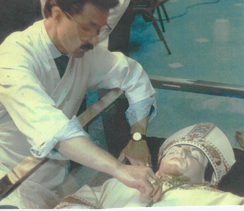 A man in a white shirt and tie is touching a statue