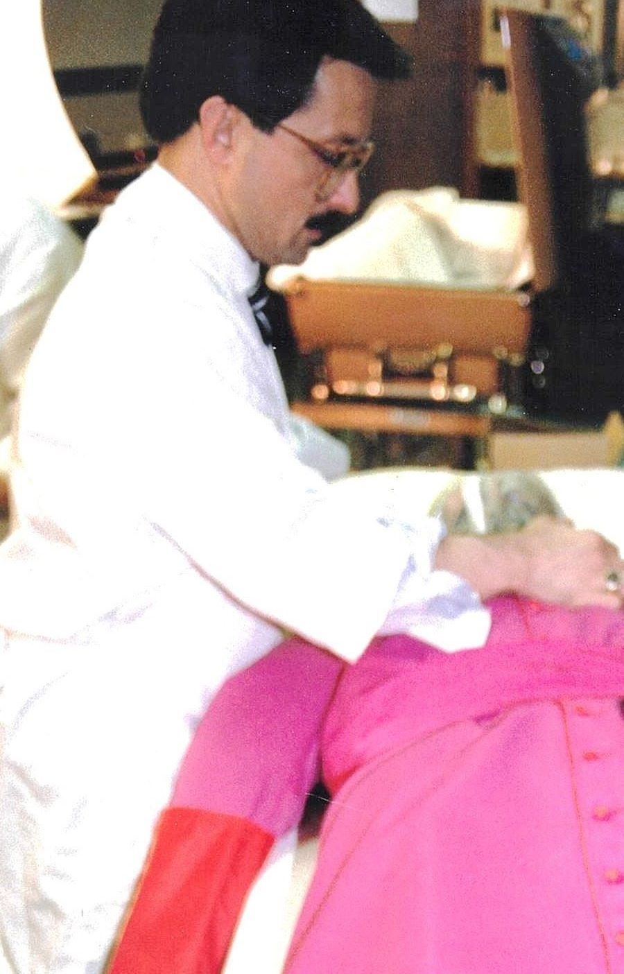 A man in a white coat is sitting next to a woman in pink pants