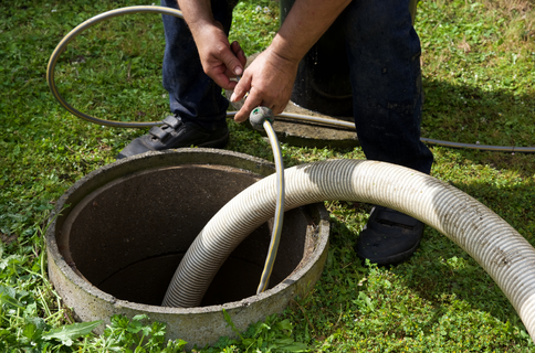 staff sticking hose down pipe for septic tank cleaning