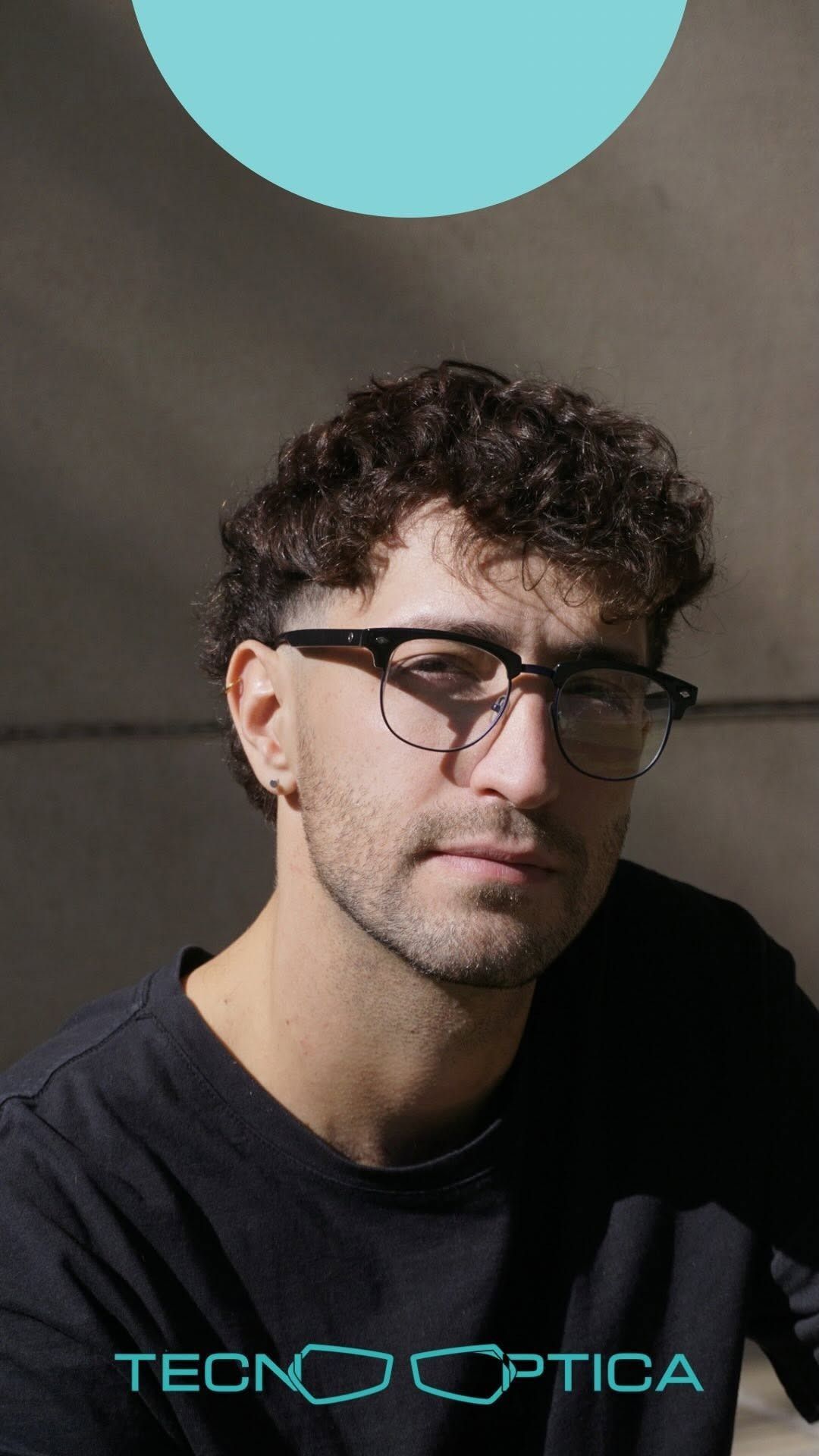 Hombre con gafas y camiseta oscura. Círculo verde azulado arriba. Fondo gris, sombra. Logotipo de TECNO OPTICA.