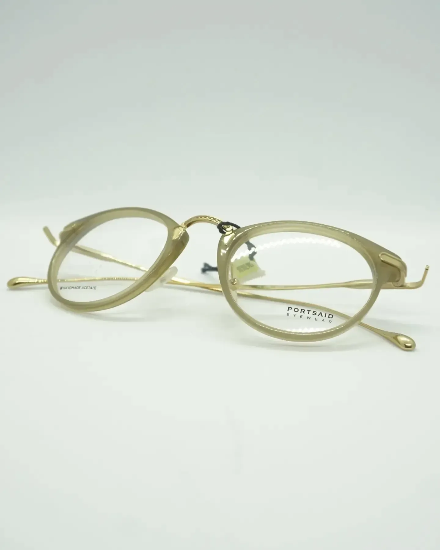 Gafas con montura dorada y lentes ovaladas sobre fondo blanco.