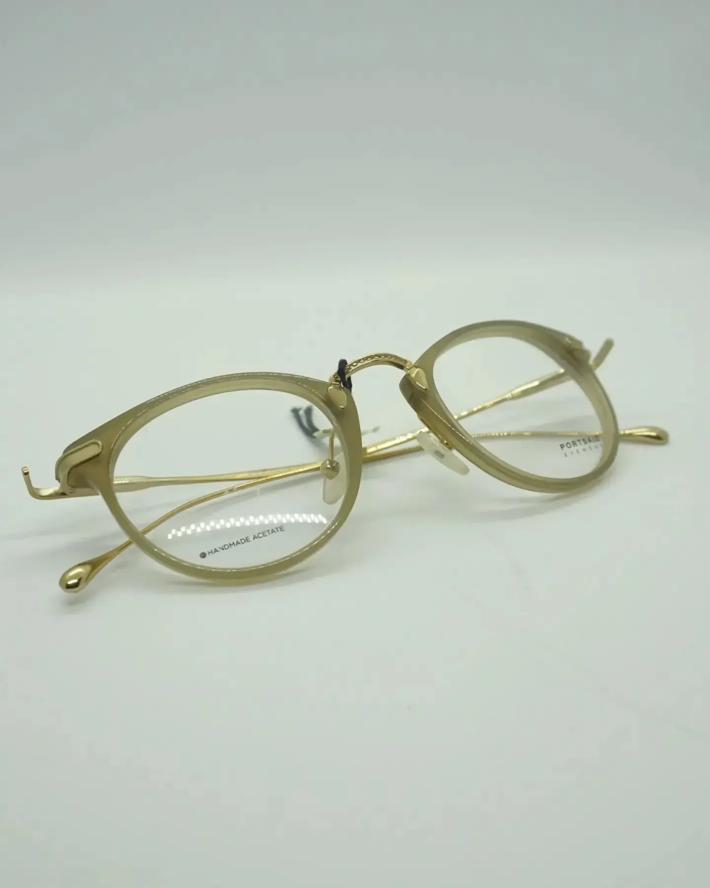 Gafas con montura dorada sobre superficie blanca, con lentes redondas y patillas delgadas.