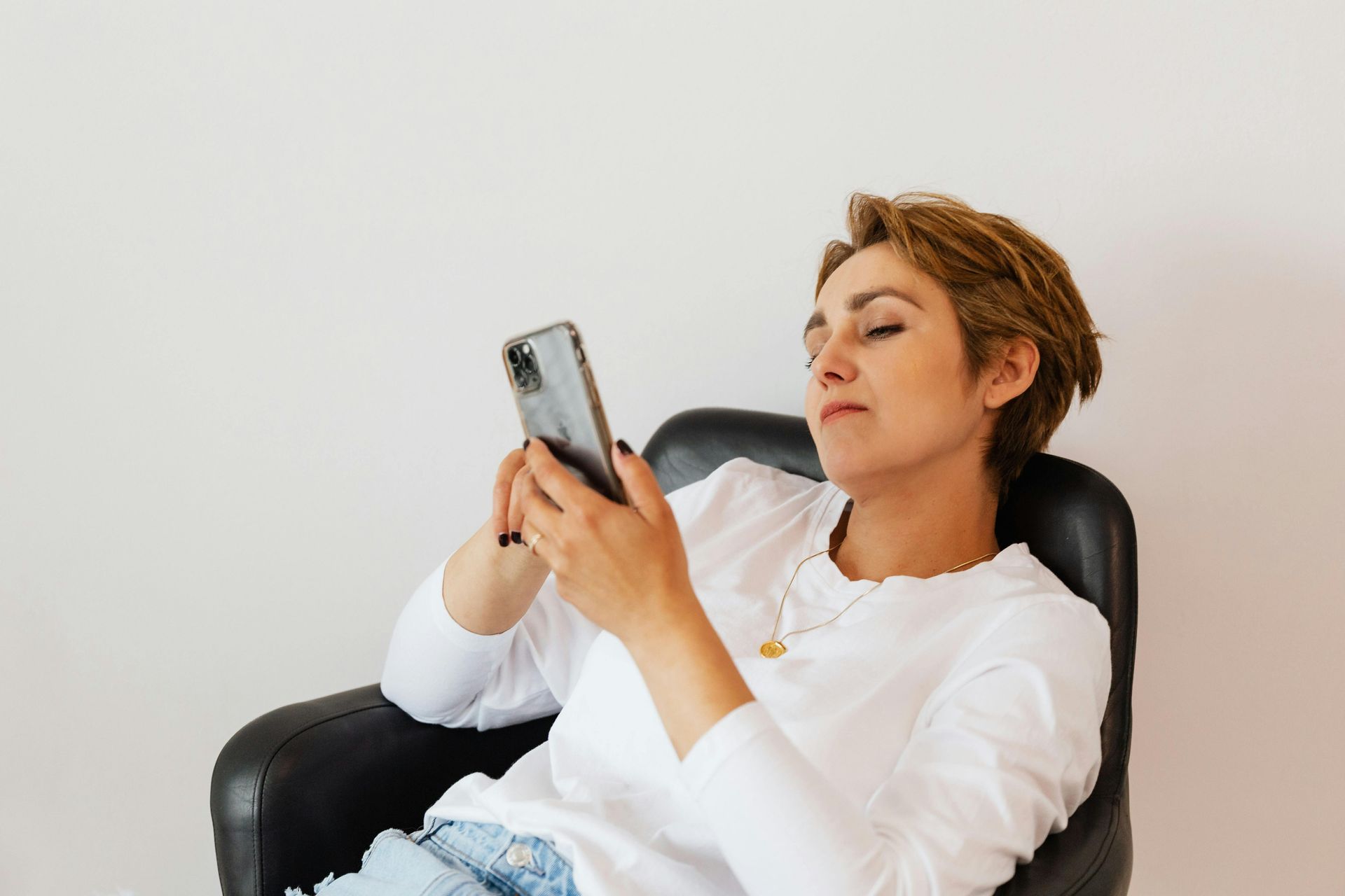 Image of a woman scrolling on her phone sitting in a desk chair. Click to read more about social media content tips!