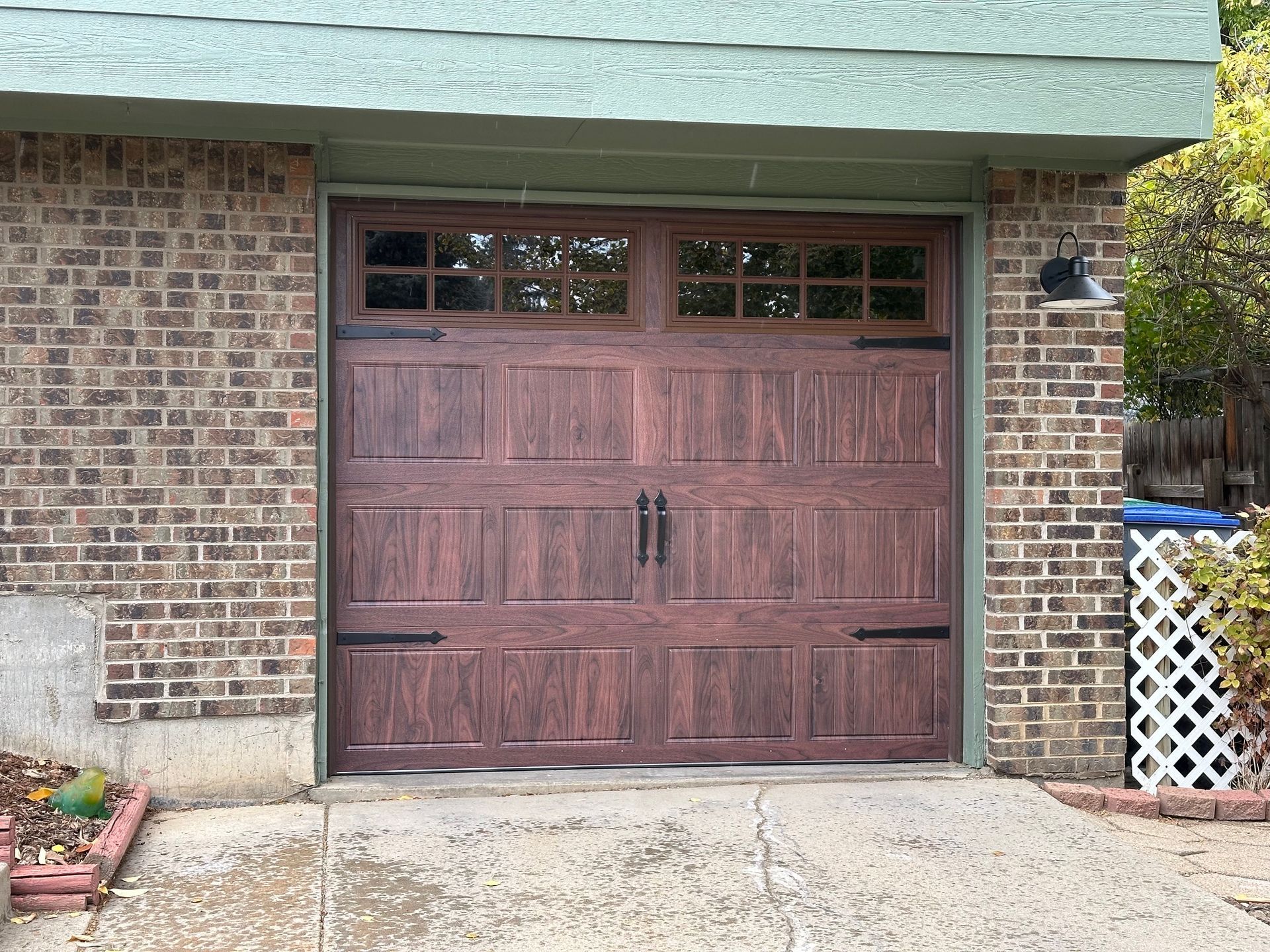 Walnut carriage garage door with stockton window panels set in brick structure.
