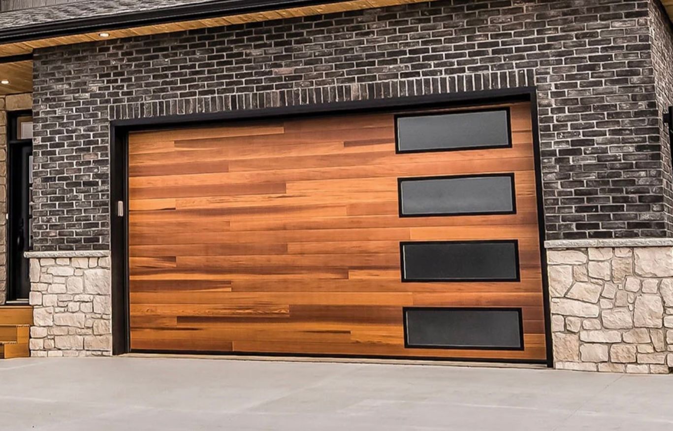 Modern cedar plank garage door with rectangular windows set in brick and stone facade.