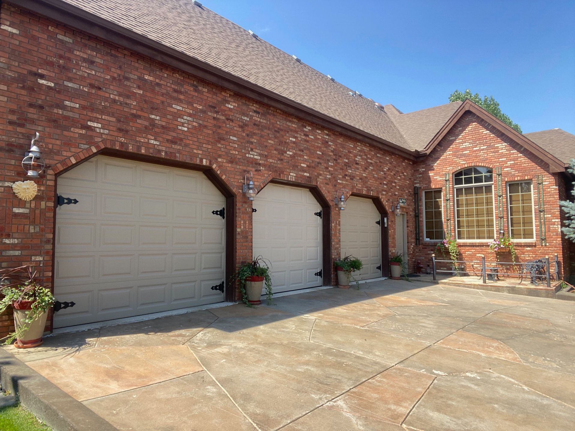 Three-car brick garage with beige doors, on a sunny day.