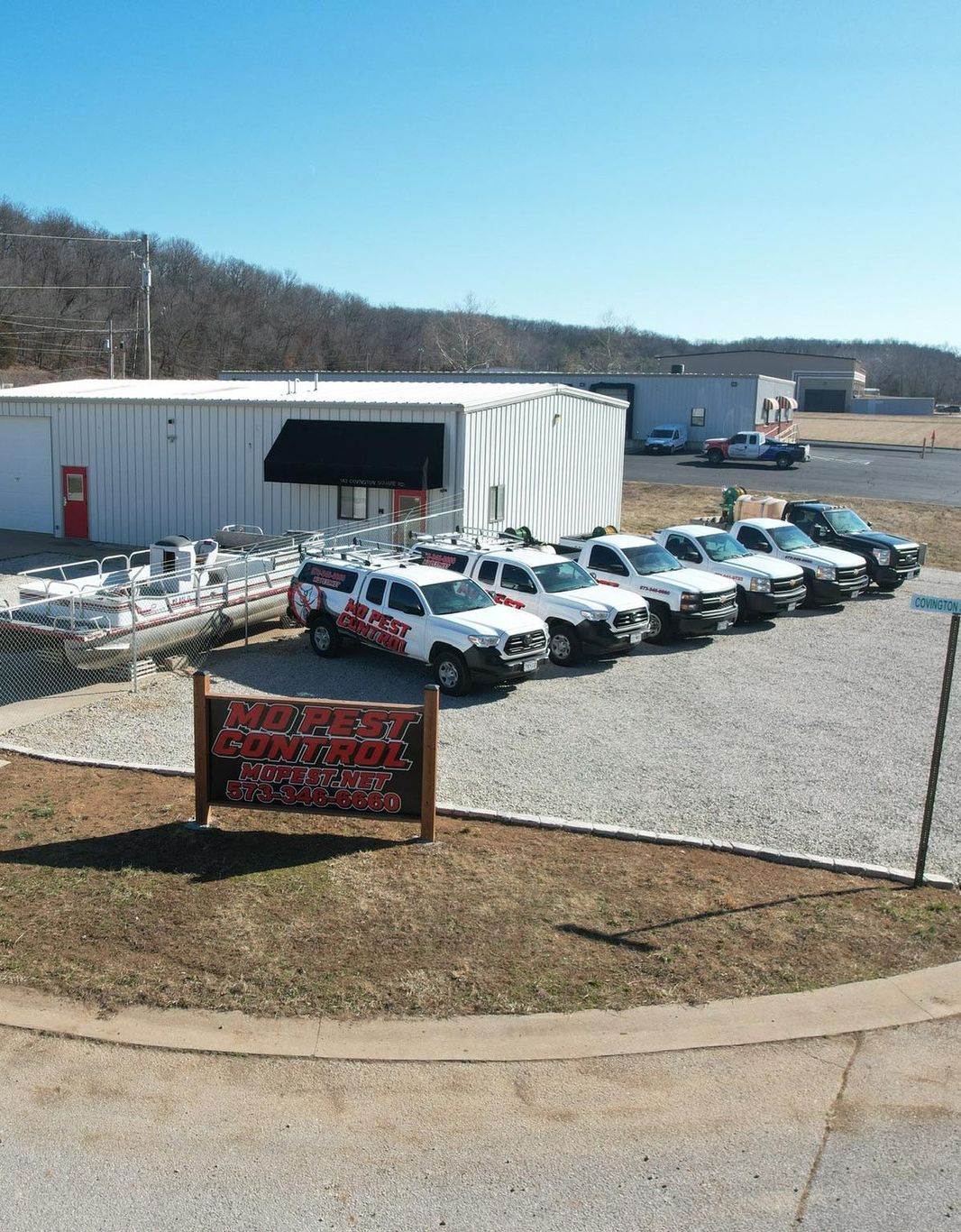 A row of white trucks are parked in front of a building. Missouri Pest Control (MOPEST)