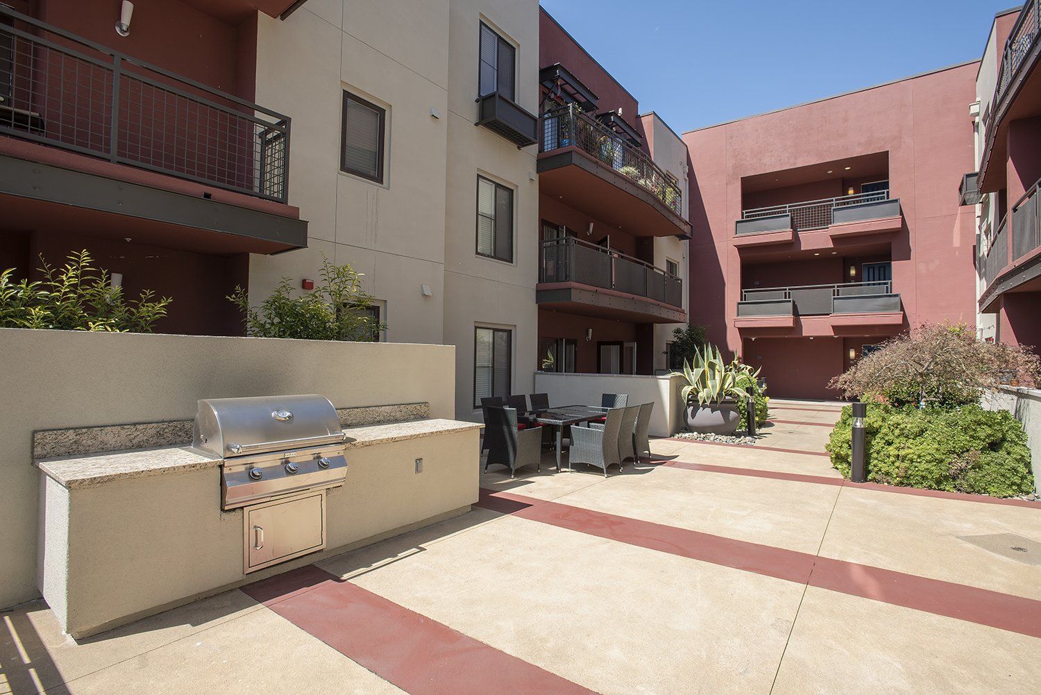 El Cerrito, CA Apartments - Metro 510 - BBQ Grill Area With A Table, Chairs, Gas BBQ Grill, And Maintained Landscaping.
