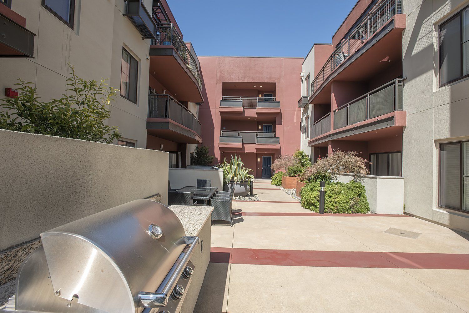 El Cerrito, CA Apartments - Metro 510 - BBQ Grill Area With A Table, Chairs, Gas BBQ Grill, And Maintained Landscaping.