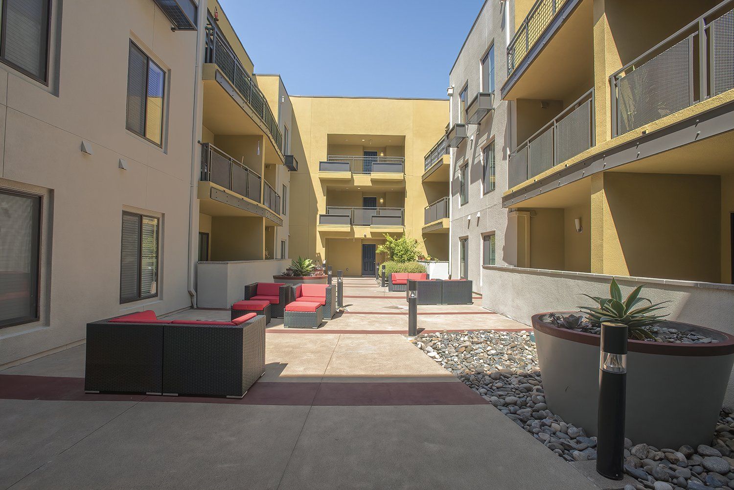 El Cerrito Apartments - Metro 510 - Courtyard In The Heart Of The Complex. The Courtyard Has Plush Seating, Stools, Lights, Potted Plants, And Maintained Landscaping.
